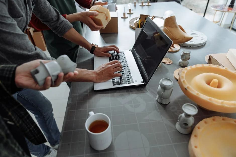 Hands on laptop with 3D prototypes, visualizing the engineering behind a B2B startup's GTM stack.