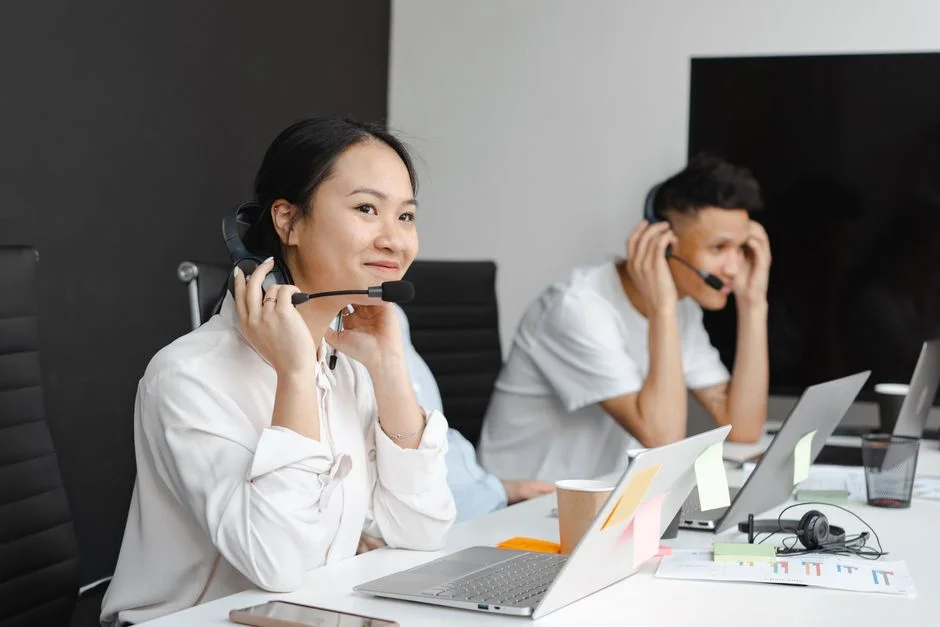 Diverse team of customer service representatives wearing headsets and working on laptops in a bright, modern office spac