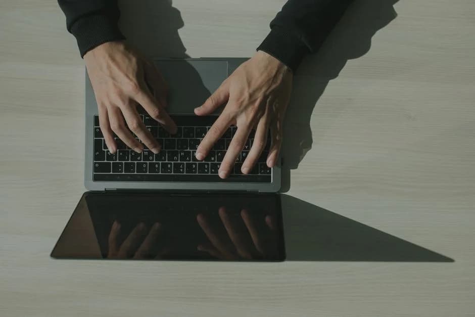 Overhead view of hands typing on a laptop keyboard.