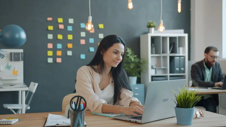 Two professionals collaborating at laptops in a bright creative office, representing enterprise demand generation strate