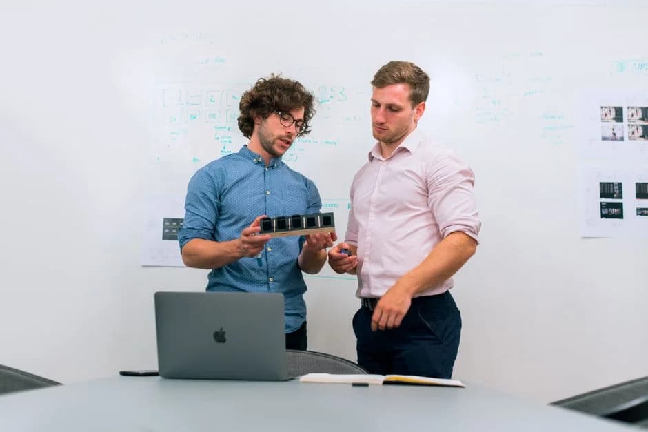 Two professionals collaborating over a device in a modern office meeting