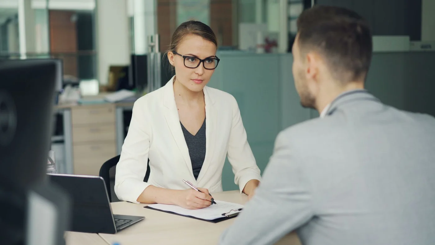 Two professionals in conversation across an office desk
